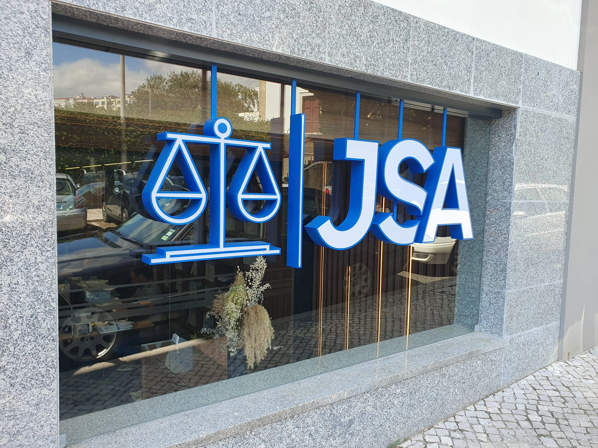 Letras 3D com iluminação lateral LED e face opaca azul, instaladas em montra de vidro para escritório JSA.