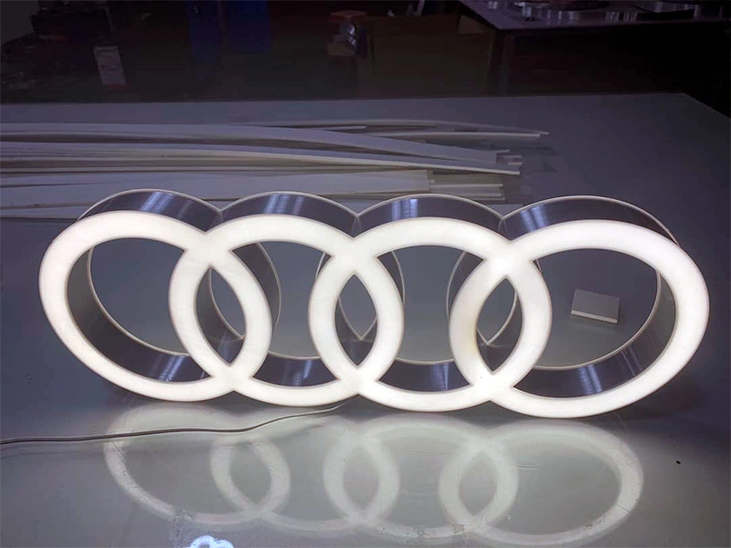 Logótipo Audi com anéis em acrílico opalino para iluminação frontal branca e laterais em aço inox polido.